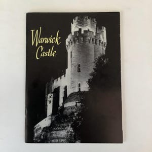 May include: A postcard featuring Warwick Castle, with the castle tower illuminated against a dark background. The text "Warwick Castle" is in a gold script font at the top left of the postcard.