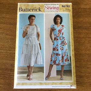 May include: Butterick sewing pattern B6722. The package features two dress designs: one striped and one floral. The dresses have a tiered skirt and a belted waist. The package is designed and printed in the USA.