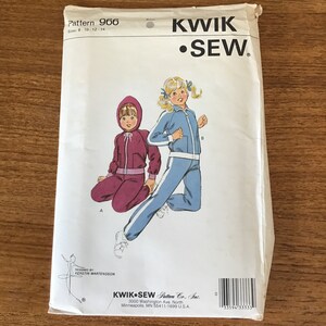 May include: A Kwik Sew pattern envelope showing illustrations of children's tracksuits. The pattern includes sizes 8-14. One tracksuit is burgundy, and the other is light blue with white stripes. The brand name "KWIK SEW" is prominently displayed.