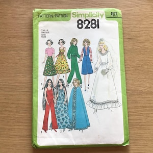May include: A Simplicity 8281 sewing pattern envelope with a light green border. The front displays illustrations of eight different outfits for dolls, including dresses, a jumpsuit, a cape, and a wedding gown with a veil, labeled with numbers.