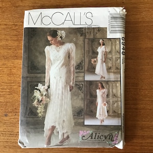 May include: A vintage McCall's sewing pattern for wedding dresses. The pattern features three different bridal gown designs, each with unique lace and embellishments. The cover showcases a bride in a long-sleeved, lace gown holding a bouquet.