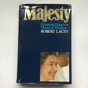 May include: A blue hardcover book titled "Majesty: Elizabeth II and the House of Windsor" by Robert Lacey. The cover features a photo of Queen Elizabeth II smiling.