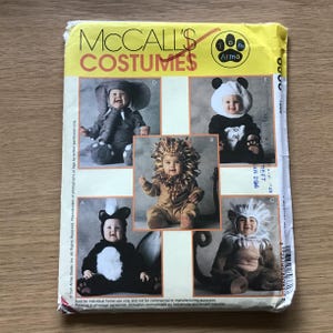 May include: A vintage McCall's Costumes sewing pattern featuring five different animal costumes for babies. The costumes include an elephant, lion, panda, monkey, and skunk. The pattern is printed on yellow paper with a Tom Arma logo.