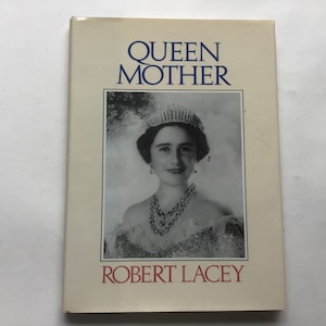 May include: A hardcover book titled "Queen Mother" by Robert Lacey. The cover features a black and white portrait of a woman wearing a tiara and jewelry. The book has a cream-colored background with blue and red text.