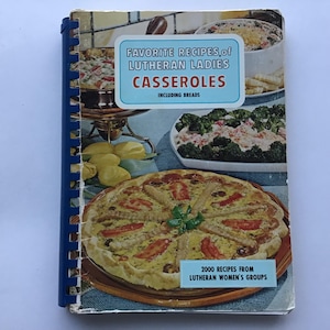 May include: A vintage cookbook titled "Favorite Recipes of Lutheran Ladies Casseroles Including Breads." The cover features images of casseroles and a quiche. The book has a blue spiral binding and is slightly worn.