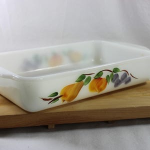 May include: White rectangular baking dish with a hand-painted design of fruit and leaves. The dish is on a wooden cutting board.