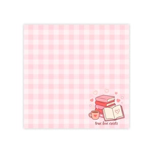 May include: A pink and white gingham patterned square with a stack of books, a coffee cup, and an open book with a heart illustration. The words "true love exists" are written below the illustration.