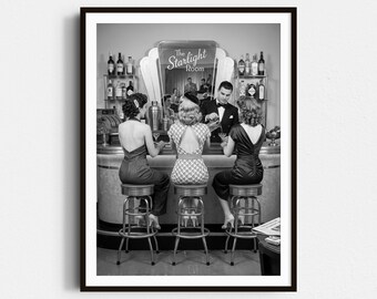 Può includere: Fotografia in bianco e nero di una scena di bar vintage. Tre donne sono sedute al bar, mentre un barista in smoking prepara dei drink. Il bar ha un design retrò con un'insegna che recita "The Starlight Room."