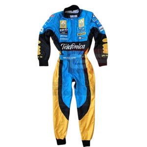 May include: A blue, black, and yellow racing suit featuring the text Telefonica, Renault, and Fernando Alonso. The garment includes long sleeves, a high collar, and various sponsor logos printed across the chest, shoulders, and arms in a vibrant color scheme.