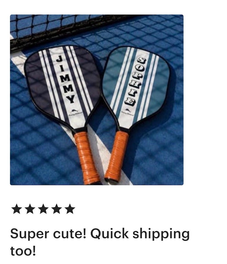 Peut inclure: Deux raquettes de pickleball avec des poign&eacute;es en similicuir marron. La raquette de gauche est bleu fonc&eacute; avec des rayures verticales blanches et le nom JIMMY. Celle de droite est bleu clair avec des rayures blanches et le nom SOPHIE.