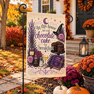 Peut inclure: Un drapeau de jardin rectangulaire avec un fond crème et des illustrations violettes et noires représentant un chapeau de sorcière, un gâteau au chocolat, une bouteille de lavande, une bougie et un livre intitulé Amas Veritas. Le texte indique In this house we eat chocolate cake for breakfast.
