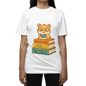 May include: White t-shirt featuring a cartoon hamster wearing glasses and reading a book. The hamster sits atop a stack of books with titles like "Hamster History" and "Adventures in Tiny Worlds."