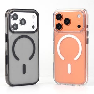 May include: Two phone cases. One is gray with a black border, the other is clear with an orange back. Both cases have a white circular design and a small rectangle at the bottom, likely for magnetic charging.