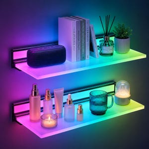 May include: Two illuminated floating shelves with a gradient LED light display. The top shelf holds a speaker, books, and a diffuser with reeds and a small potted plant. The bottom shelf displays beauty products, a candle, and a glass mug.