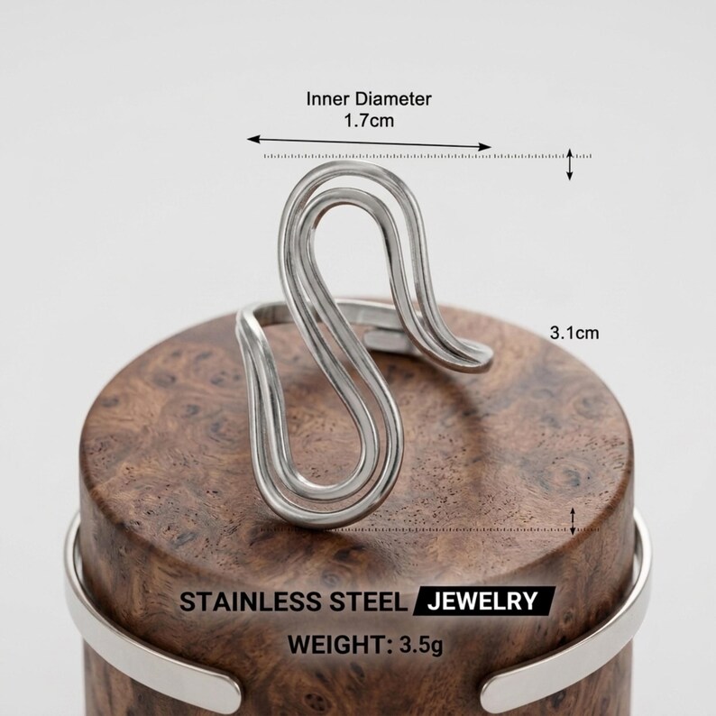 May include: A silver-toned stainless steel ring with a wavy, open-ended design. The ring features an inner diameter of 1.7 cm and a total height of 3.1 cm. The text on the image reads STAINLESS STEEL JEWELRY and WEIGHT: 3.5g.
