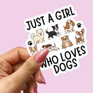 以下が含まれることがあります： 「JUST A GIRL WHO LOVES DOGS」の文字と様々な犬種のイラストが描かれたステッカー。白い縁取りがあり、ピンク色の背景に配置されています。