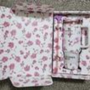 Puede incluir: Un juego de regalo con tem&aacute;tica floral que incluye una taza blanca con dise&ntilde;os de flores rosas, una cuchara a juego y un posavasos. La taza tiene la palabra "Forever" impresa. El juego se presenta en una caja decorativa con un patr&oacute;n floral a juego.