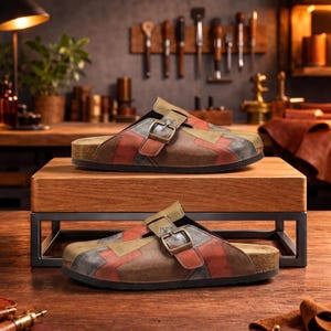 Peut inclure: Deux paires de sabots en cuir patchwork avec fermetures à boucle. Les sabots présentent un mélange de patchs en cuir marron, rouge et beige. Les semelles sont en liège. Les sabots sont exposés sur un présentoir en bois.