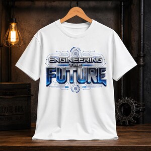 May include: White t-shirt with the words "ENGINEERING THE FUTURE" in a blue and silver futuristic design. The design includes circuit board-style graphics. The shirt is hanging on a wooden hanger.