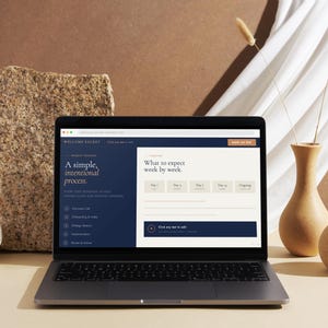 May include: A handmade wooden sign with the text "Welcome" in a playful font. The sign is painted white with a distressed finish, and features a decorative floral design in shades of pink and green. It measures approximately 12 inches wide and 6 inches tall.