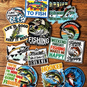 Könnte beinhalten: Eine Sammlung bestickter Stoffaufnäher mit verschiedenen Angelmotiven, farbenfrohen Fischillustrationen und humorvollen Texten wie He Called Me To Fish, Fishing Is My Therapy und Weekend Forecast: Fishing Makes Me Happy.