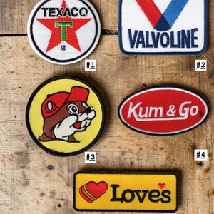 May include: Five embroidered patches featuring brand logos and mascots. Patch #1 is a round Texaco logo. Patch #2 is a rectangular Valvoline logo. Patch #3 is a round yellow patch with a beaver mascot. Patch #4 is an oval Kum & Go logo. Patch #5 is a rectangular yellow Love's patch with a heart.
