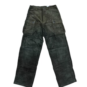 May include: Dark olive green corduroy cargo pants with multiple pockets. The pants have a button and zipper closure and a relaxed fit. The corduroy fabric has a subtle sheen, and the pants appear to be unworn.