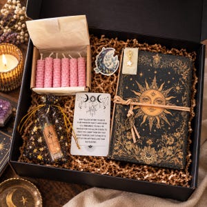 May include: A black gift box containing a black journal with a gold sun illustration, a small box of six pink honeycomb candles, a star-patterned pouch with a glass vial, a moon sticker, a star charm, and a card with printed text.