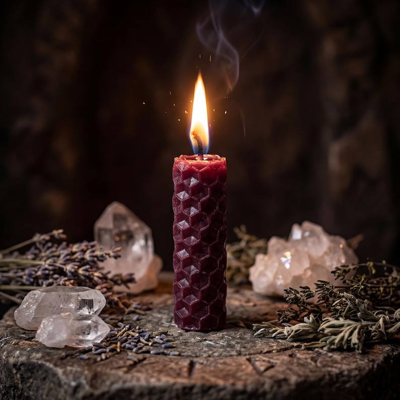May include: A deep burgundy pillar candle with a textured honeycomb pattern is lit, emitting a bright flame and thin wisp of smoke. The candle is surrounded by clear quartz crystals, dried lavender sprigs, and scattered herbs.