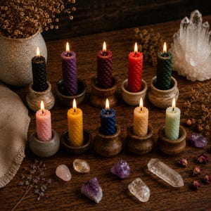 May include: Ten lit beeswax candles with a textured honeycomb pattern, each held in a small, individual ceramic or wooden holder. The candles are in various colors including black, purple, burgundy, red, dark green, pink, yellow, blue, orange, and light green.