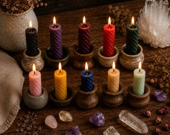May include: Ten lit beeswax candles with a textured honeycomb pattern, each held in a small, individual ceramic or wooden holder. The candles are in various colors including black, purple, burgundy, red, dark green, pink, yellow, blue, orange, and light green.