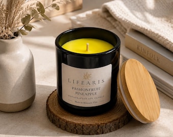 May include: A black glass candle jar filled with bright yellow wax and a single wick. The label reads "LIFEARIS PASSIONFRUIT PINEAPPLE HANDCRAFTED SOY CANDLE Made in Missouri, USA". A round wooden lid rests beside the jar on a circular wood slice coaster.