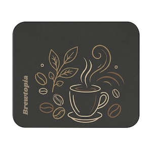 May include: A rectangular dark grey mouse pad featuring a light brown line art illustration of a steaming coffee cup, coffee beans, and a leafy branch. The text Brewtopia is printed vertically in light brown on the left side of the pad.