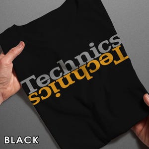 May include: Black t-shirt with the word "Technics" printed diagonally in gray and yellow. The word "BLACK" is printed at the bottom of the shirt.