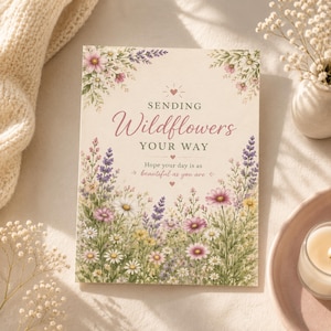 Può includere: Un biglietto d'auguri rettangolare con sfondo color crema caratterizzato da un'illustrazione ad acquerello di fiori di campo colorati, tra cui lavanda, margherite e fiori rosa. Il testo recita: SENDING Wildflowers YOUR WAY Hope your day is as beautiful as you are.