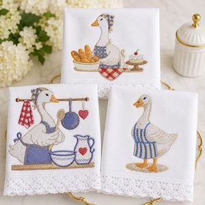 Puede incluir: Juego de tres paños de cocina blancos con diseños de gansos bordados. Cada paño presenta una escena de ganso diferente: horneando con pan, pastel y utensilios de cocina. Las toallas tienen un ribete de encaje.