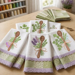 Può includere: Un set di strofinacci bianchi con ricami di cucchiai di legno legati con nastri a mazzetti di erbe e fiori. Ogni strofinaccio presenta un bordo in tessuto patchwork verde e bianco rifinito con pizzo viola chiaro sul bordo inferiore.