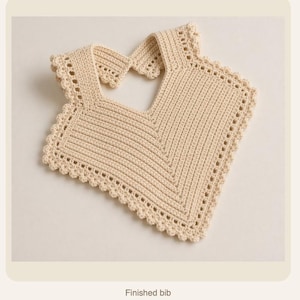 May include: A cream-colored, crocheted bib with a scalloped edge and a V-neck design. The bib has a rectangular shape with a neck opening and is made of a soft, textured yarn. The text "Finished bib" is at the bottom.