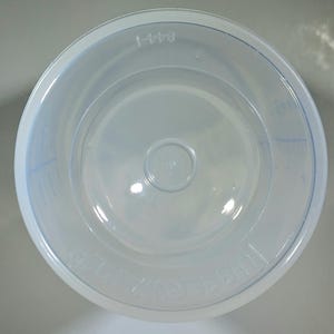 May include: A clear, round plastic container with a slightly flared rim. The container has a circular base and a small, raised circle in the center. The text "844-1" is printed on the rim. The word "TUPPERWARE" is also visible.