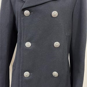 May include: A navy blue double-breasted coat with six decorative silver buttons. The coat has a notched lapel collar and two front pockets. The coat is made of a wool blend and is a classic style.