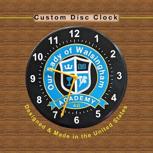 May include: A round black clock with a blue and white emblem in the center. The clock face has white numbers and yellow hands. The text "Custom Disc Clock" is at the top, and "Designed & Made in the United States" is at the bottom.