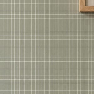 May include: A sage green wall covering featuring a repeating grid pattern of thin white vertical and horizontal lines. A portion of a light-colored wooden frame is visible in the upper right corner, partially overlapping the grid-patterned surface.