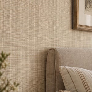 May include: A beige wallpaper with a subtle cross-hatched texture featuring thin intersecting lines. The wall is positioned behind a light gray upholstered headboard with a decorative pillow and a framed artwork hanging on the right side.