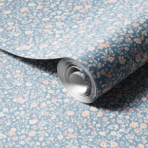 May include: A roll of floral wallpaper featuring a pattern of small pink and white flowers and green leaves on a blue background. The wallpaper is rolled up, revealing the pattern and texture.