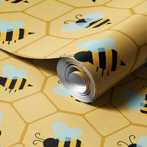 May include: A roll of wallpaper featuring a repeating pattern of black and yellow striped bees with light blue wings set against a mustard yellow background with a geometric honeycomb grid of slightly darker yellow lines throughout the design.