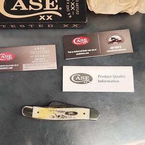 May include: A folding pocket knife with a cream-colored handle featuring a textured finish and silver metal bolsters. The set includes a black Case XX branded box, a piece of crumpled tan paper, and three informational cards with Case XX branding.