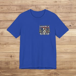 May include: A royal blue short-sleeve t-shirt featuring a small graphic on the left chest. The design includes a soccer ball, a rooster, and the text "FRANCE EST. 2018" in a shield-shaped emblem with red, white, and blue color accents.
