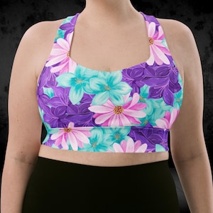 Peut inclure: Un soutien-gorge de sport à imprimé floral de style dos nu. Le soutien-gorge présente un motif de fleurs violettes, roses et turquoise. Le fond est noir.