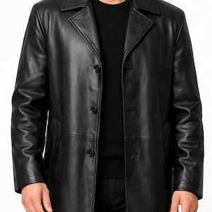 May include: A black leather overcoat with a classic design. The coat features a notched collar, three-button closure, and two front pockets. The long coat is worn over a black sweater and black pants.