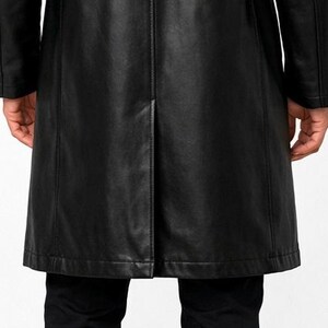 May include: A black leather coat with a classic design. The coat features a long length, a tailored fit, and visible stitching details. The image shows the back of the coat, highlighting the seams and the split at the bottom.
